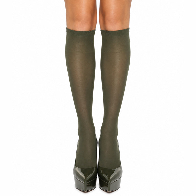 A pair of sheer olive green worn on legs, paired with dark green platform heels, shown against a plain white background.