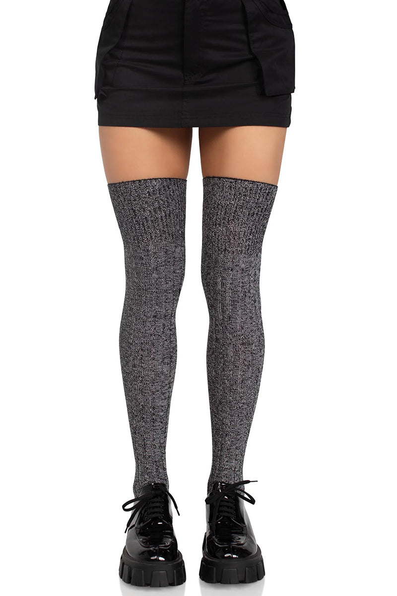 Person wearing black/white over knee-high socks with black shoes on a white background