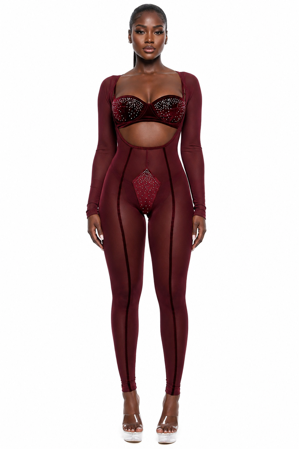 A model wearing a sheer burgundy long-sleeve bodysuit with black trim and red rhinestone embellishments on the bra and waist, paired with white platform heels, against a solid white background.