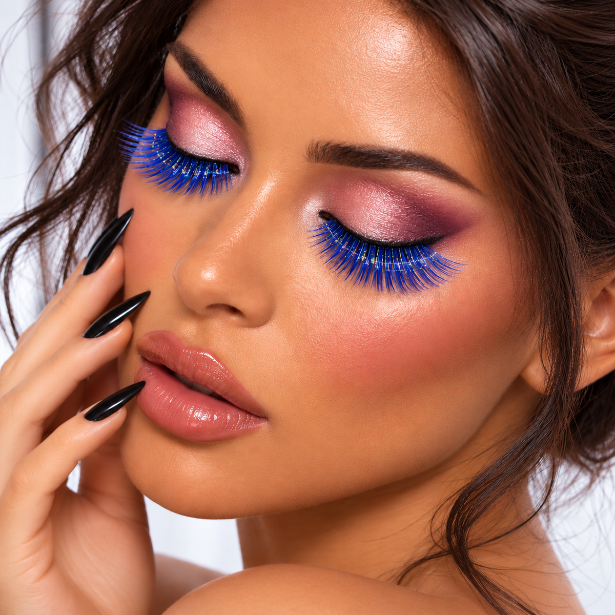 Close-up of a woman with dramatic false eyelashes, pink and purple eyeshadow, glossy lips, and black manicured nails against a light background.