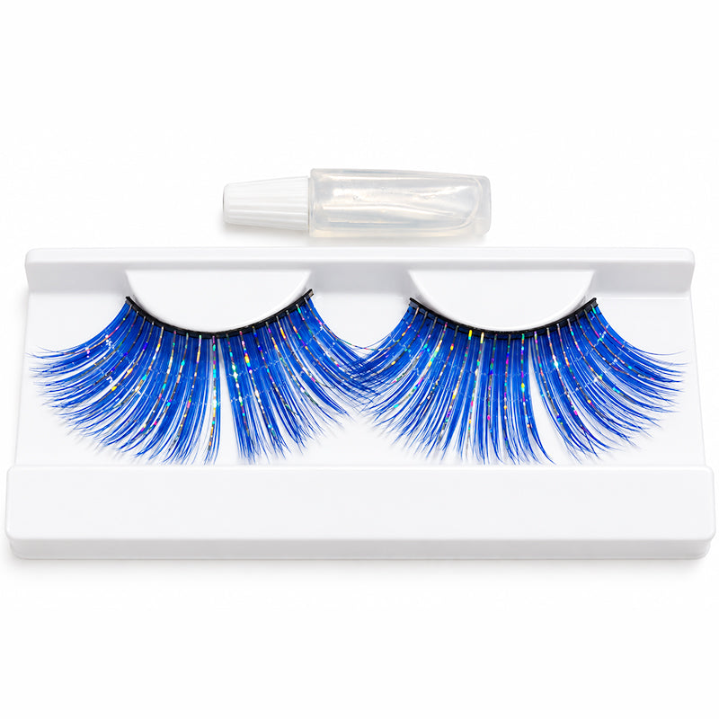 Blue false eyelashes with gold glitter accents in a white plastic tray, with a small clear bottle of adhesive above the tray.