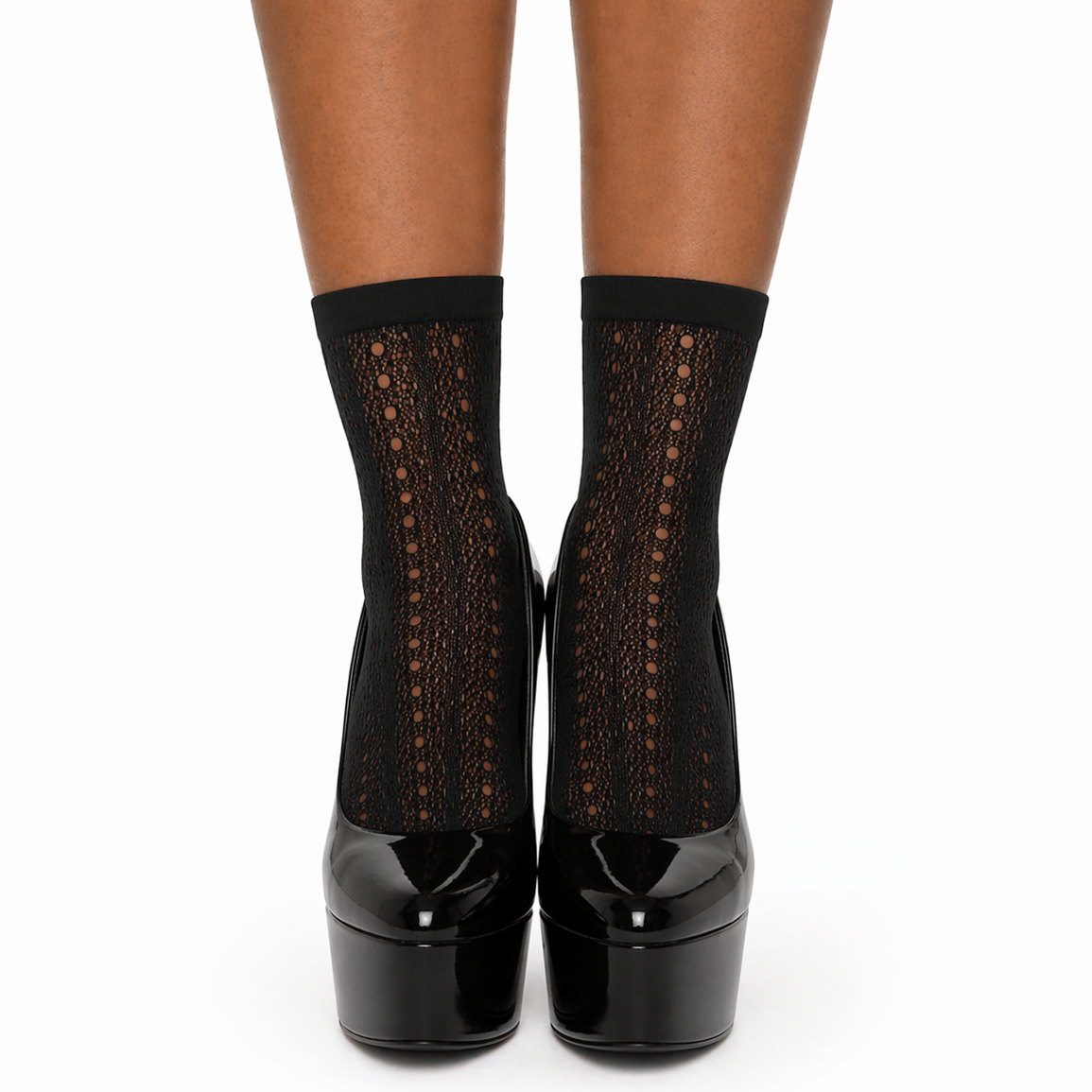 Black socks with lace details worn with black high-heeled shoes on a white background