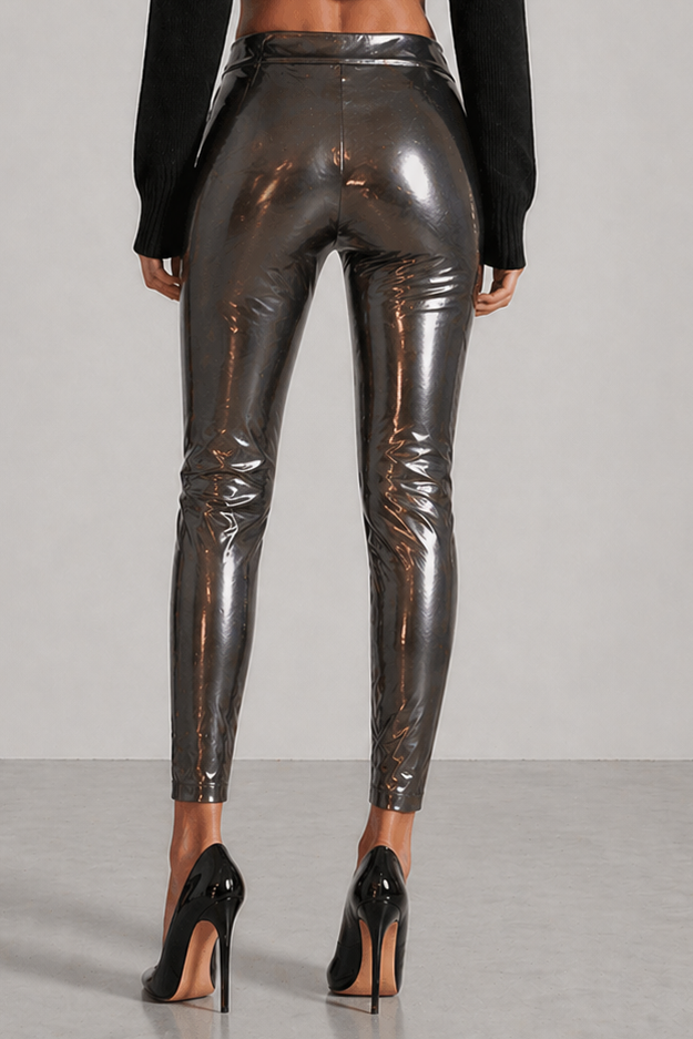 Woman wearing black turtleneck and shiny silver leggings on a gray background
