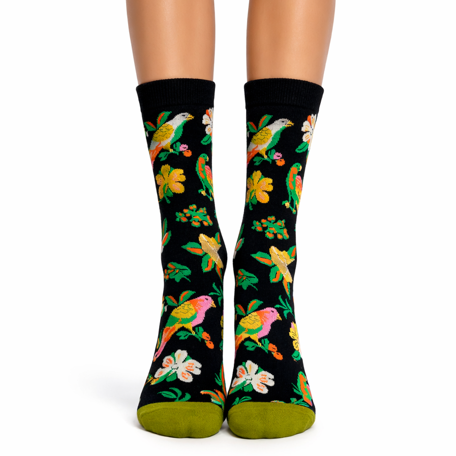 Black socks with colorful bird and flower pattern worn by a person on a white background
