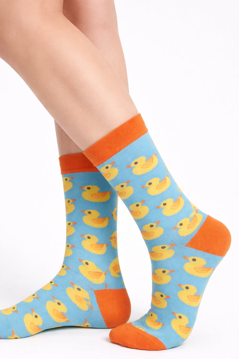 Blue socks with yellow rubber duck pattern and orange accents worn by a person on a white background