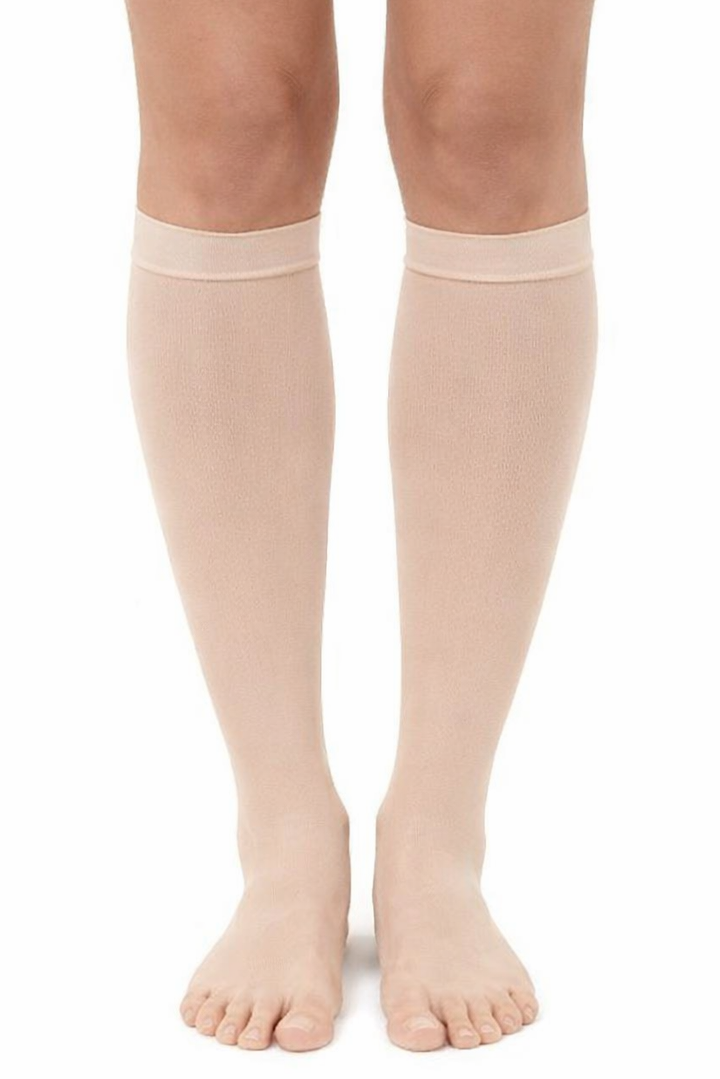Beige knee-high socks worn by a person on a white background