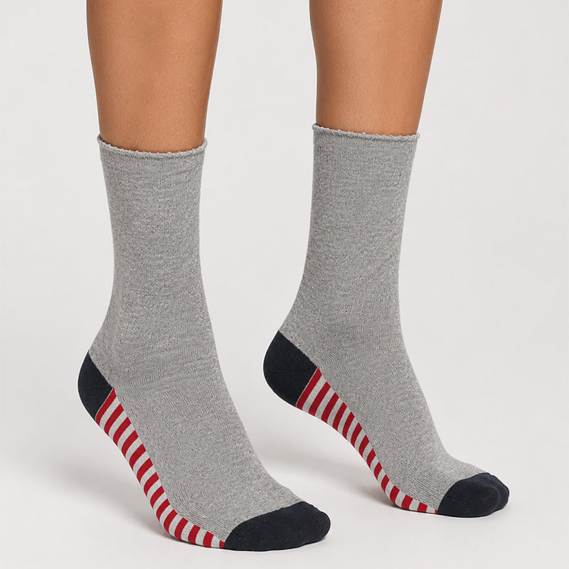 A pair of crew socks worn on feet, featuring a heather gray body with a black toe and heel, and red and white diagonal stripes along the sides.