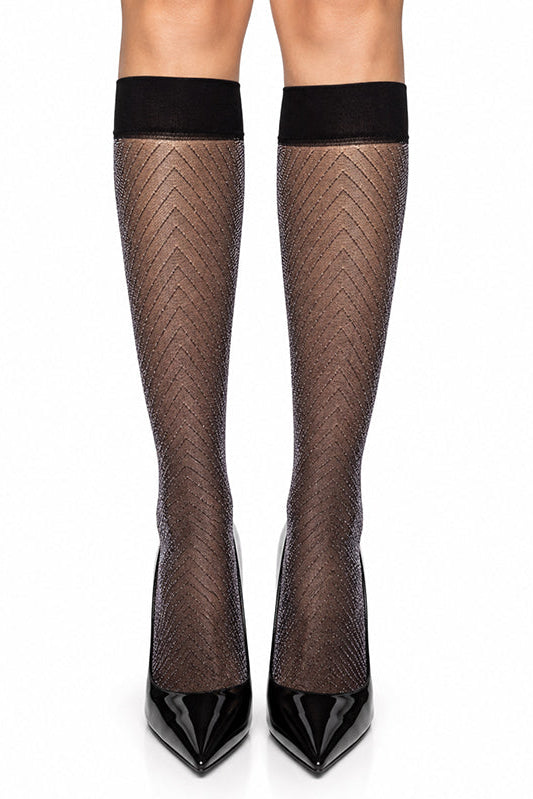Black chevron-patterned knee-high fishnet stockings worn with black pointed-toe high heels, shown on a model's legs against a white background.